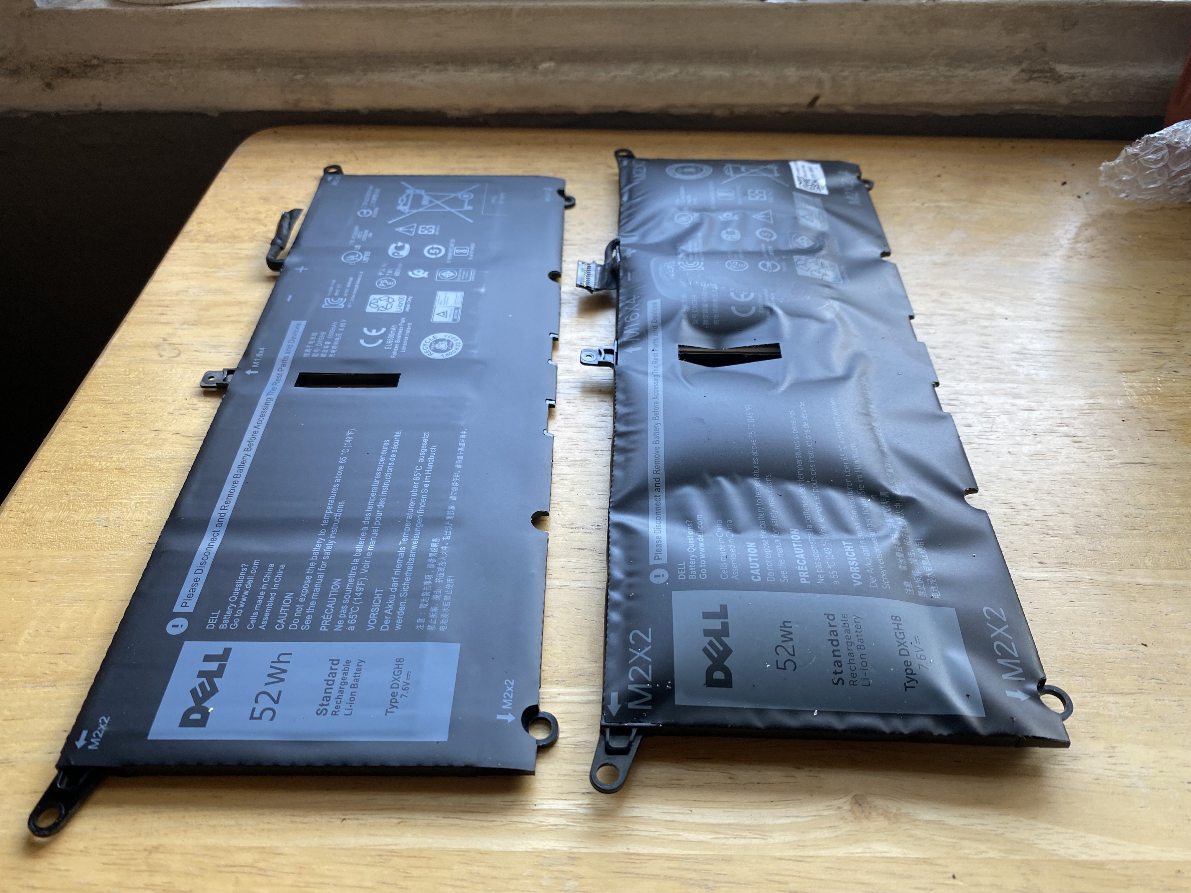 two laptop batteries side by side, one is bulging