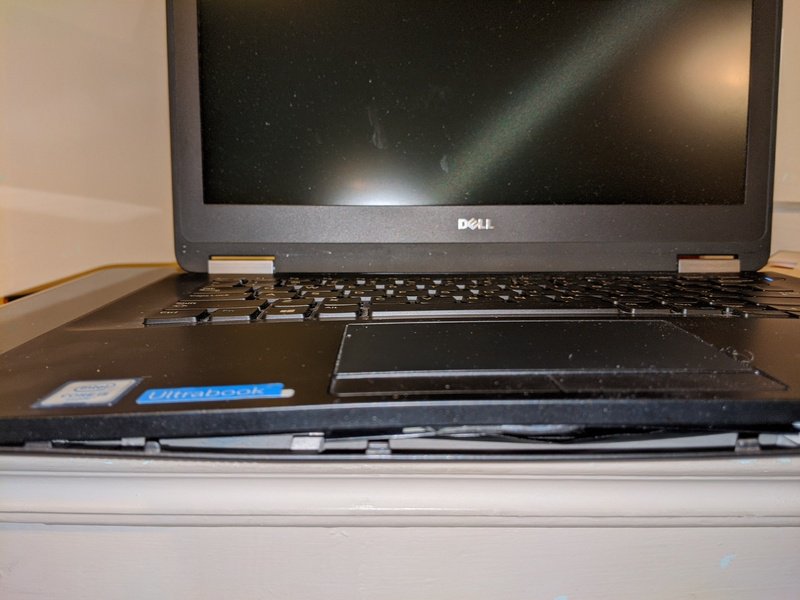 a laptop where the bottom of the case has become disconnected due to bulging