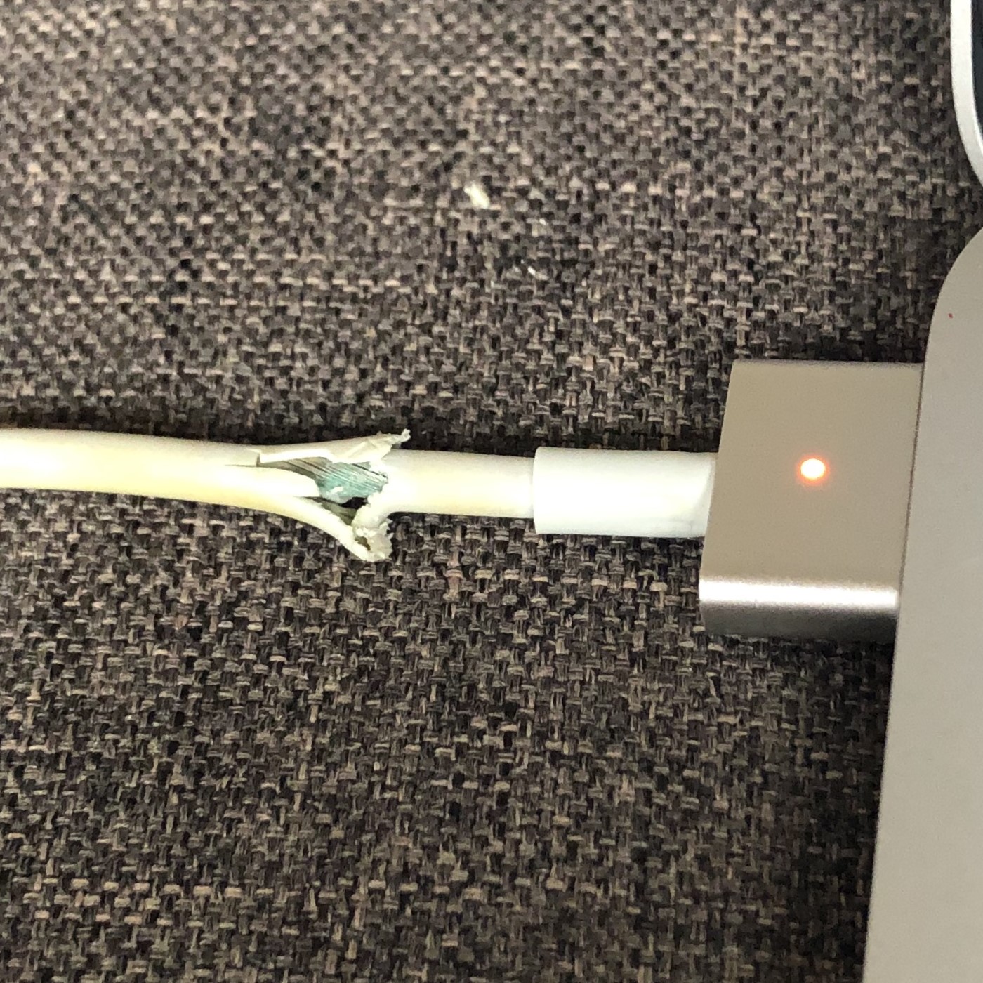 broken macbook charger exposing colored wires within