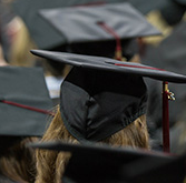 The back of a student's graduation cap during commencement with several other graduates in the background.
