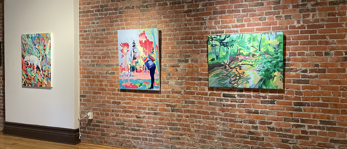 A picture of three of Erica's paintings hanging on display on a wall in an art gallery.