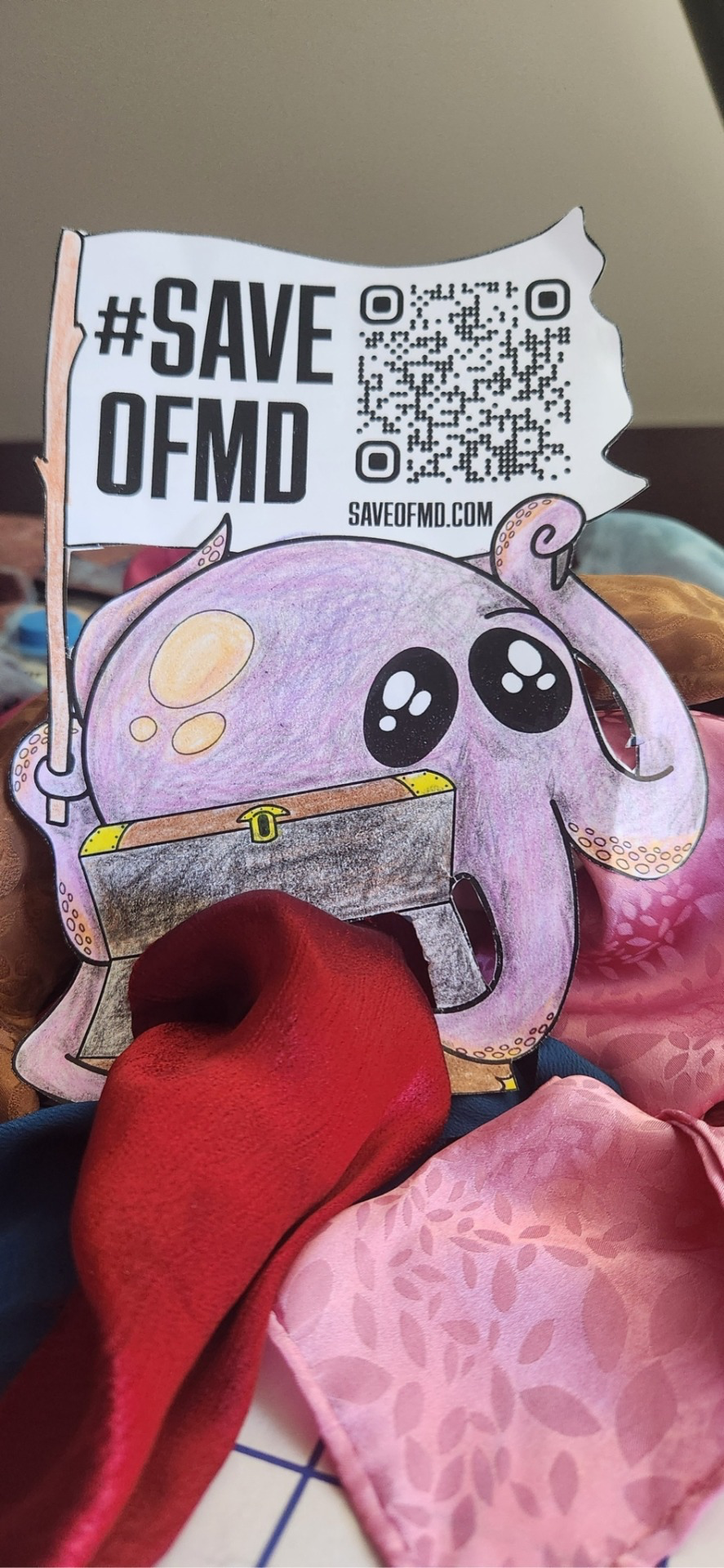 Flat Jeff the purple octopus has silky red and pink fabric in his treasure chest.