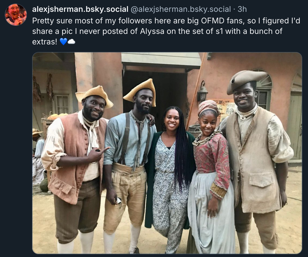 Picture of a bsky post by alexjsherman.bsky.social - Pretty sure most of my followers here are big OFMD fans, so I figured I'd share a pic I've never posted of Alyssa on the set of s1 with a punch of extras!