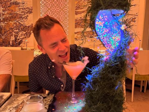 David sipping alcoholic beverage next to a goofy looking table arrangement