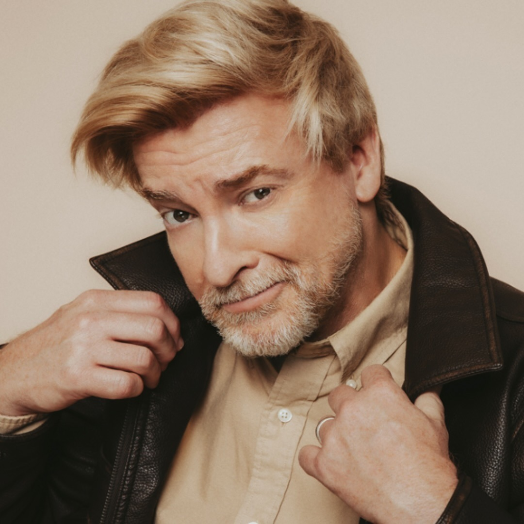 Blonde hot older gentleman with a cinnamon sugar beard holding his jacket lapels to the side in an alluring way. 