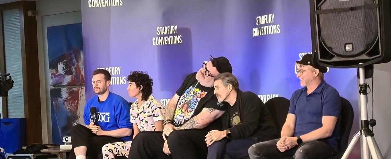 Picture of the cast sitting in front of a blue screen with star fury conventions written in white behind them. From left to right: Nathan Foad in a blue shirt holding a microphone, Vico Ortiz in a multicolored jumper, Kristian Nairn in a shirt with a colorful tiger on it, leaning over and touching heads with, Con O'Neill, black sweater over a black shirt and jeans leaning on Kristians shoulder, Rhys Darby with his hands in his lap smiling with a black had and blue polo shirt with black skinny jeans.