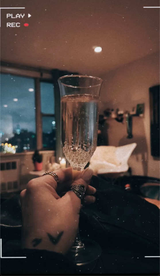 Photo of Ruibo's hand holding a champagne flute. A camera filter makes the image look noisy and darker at the edges.