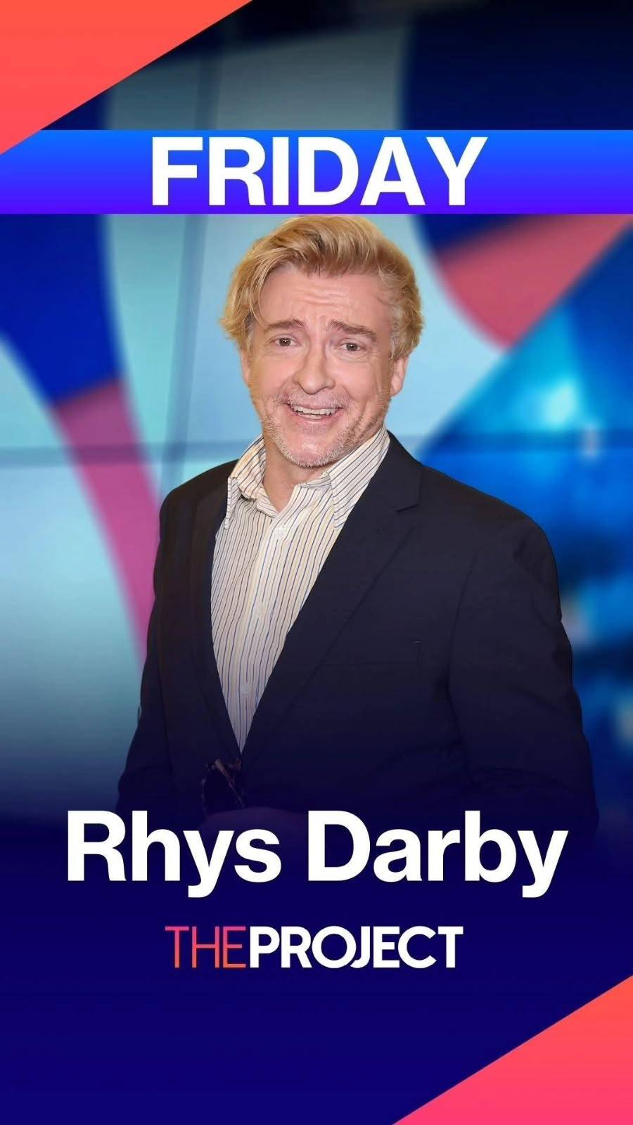 Portrait photo of Rhys shot from the hip up. He is dressed smartly in a blue & white striped button-down shirt and a dark blue suit jacket and is looking at the camera with an open-mouthed smile. 'Friday' is written in large capital letters at the top of the image, and 'Rhys Darby. The Project' at the bottom.