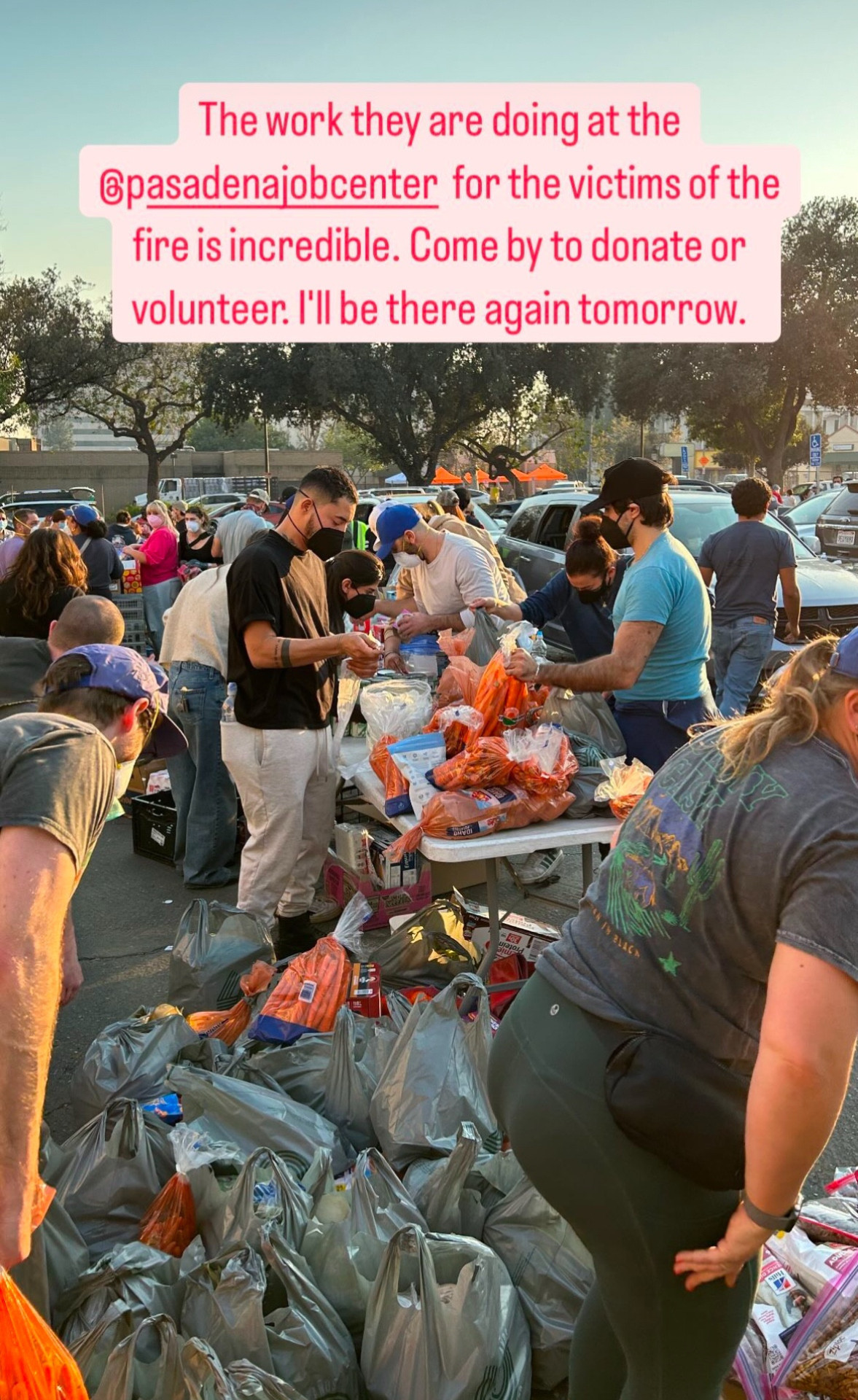 From Andrew's Instagram Stories: a photo of people handing out plastic bags of supplies to people affected by the LA fires. There are tables overflowing with bags, and yet more bags sitting on the ground next to the tables. Text at the top of the photo reads: The work they are doing at the @ PasadenaJobCenter for the victims of the fire is incredible. Come by to donate or volunteer. I'll be there again tomorrow.