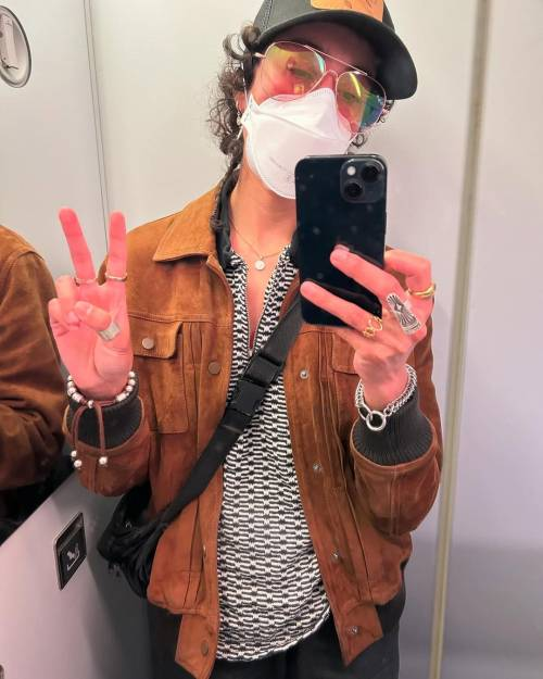 Mirror selfie of Vico Ortiz making a peace sign. They are wearing a baseball cap, an N95 mask and aviator sunglasses.