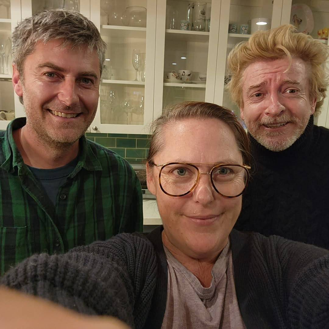 Selfie taken by Rhys' wife Rosie, with her in the foreground, and Rhys and their friend Carthew Neal behind her. They are standing in Rhys and Rosie's kitchen and all 3 of them are smiling at the camera.