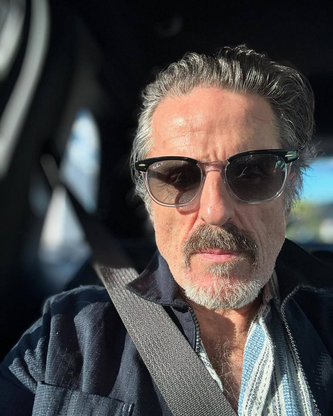 Selfie of Con sitting in a car. He is looking at the camera with a neutral expression, his eyes just visible behind a pair of sunglasses.