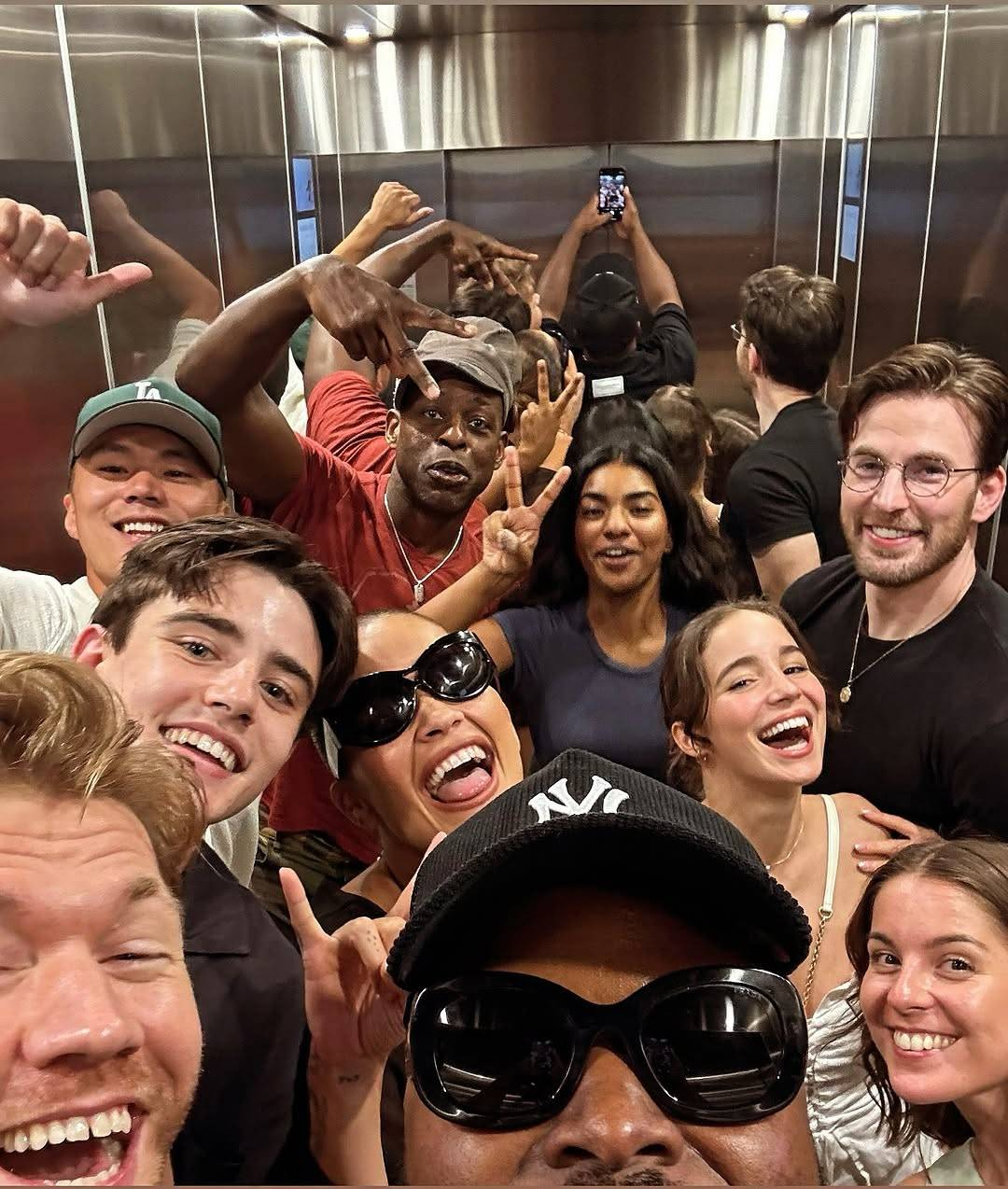 Photo of Samson and 9 other Voltron cast members inside an elevator. Only the top half of Samson's face is visible as he holds up his phone to take the picture, while everyone else is standing next to or behind him making funny faces, smiling and/or holding up a hand in a 'peace' or 'devil horns' gesture. Their reflections can be seen in the mirrored wall behind them.