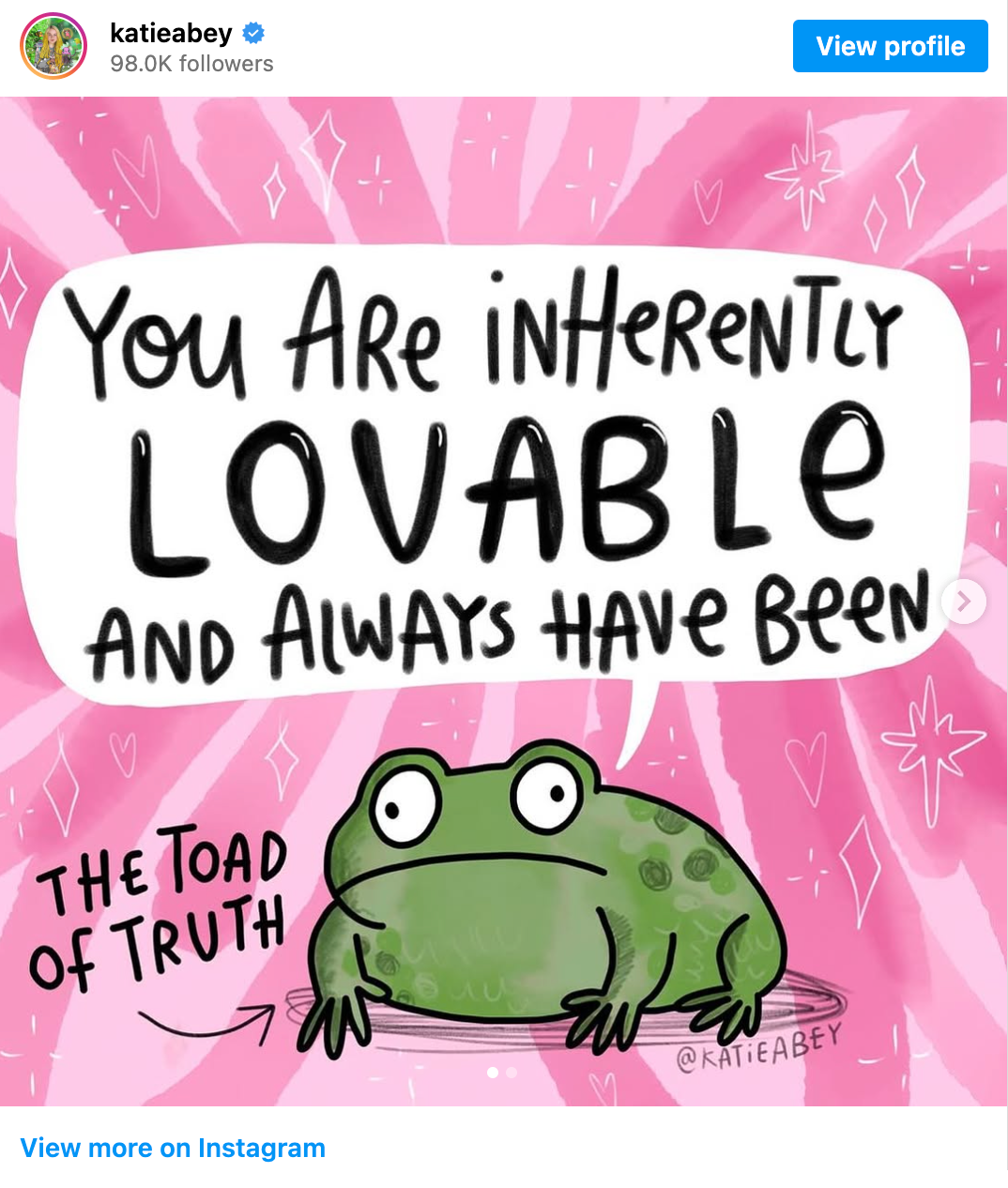 Drawing of a green toad on a pink background with white sparkly shapes and hearts drawn all over. An arrow points at the toad, labeling it 'the toad of truth'. A large speech bubble above the toad reads 'You are inherently lovable and always have been', with the word 'lovable' written in particularly big capital letters for emphasis. The artist's handle 'KatieAbey' is at the bottom of the drawing.