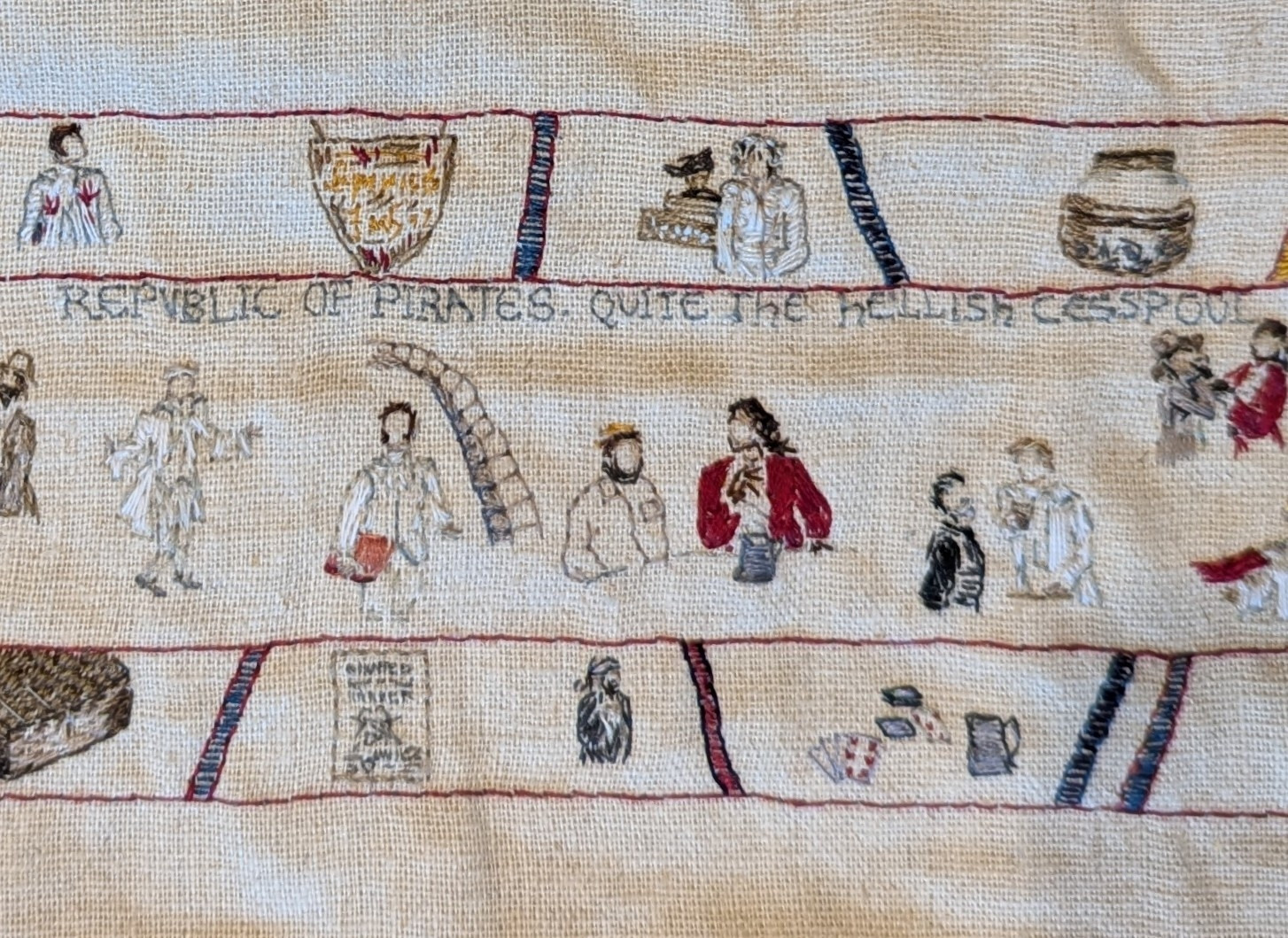 Close up showing several scenes at Spanish Jackie's bar: Stede posing as Lucius introduces him to the patrons, Jackie & Olu sitting at a table, Izzy & Stede talking, and Jackie holding a knife to Jim's throat. The line 'Republic of Pirates. Quite the hellish cesspool' is embroidered at the top.