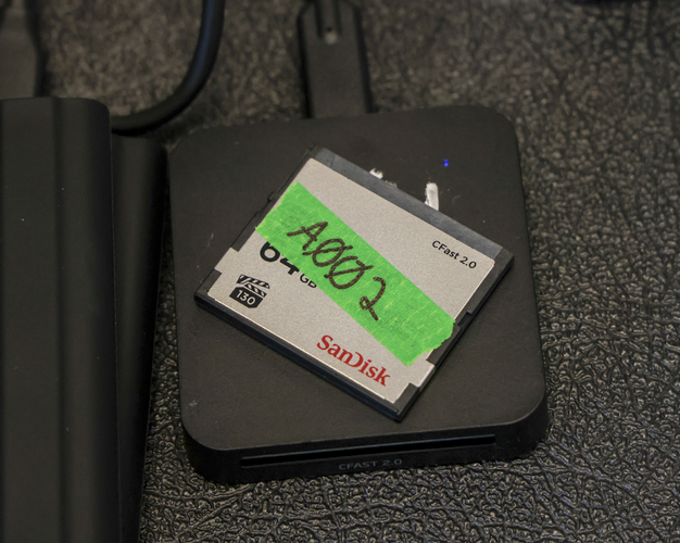 A CFast2.0 card with green tape labeled "A002".
